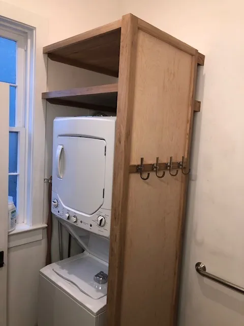Oak washer and dryer enclosure in a boutique bathroom